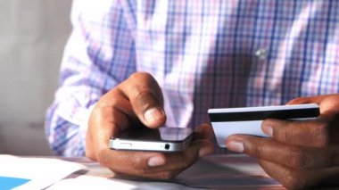 Kredi kartı tutan ve akıllı telefon kullanan bir adam, online alışveriş konsepti