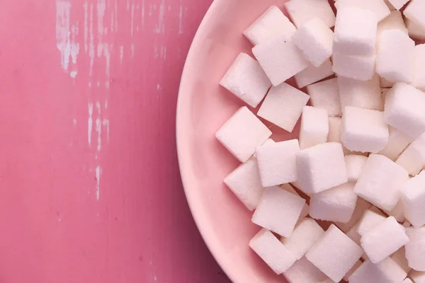 Close-up van suiker kubus in een plaat op roze achtergrond. — Stockfoto