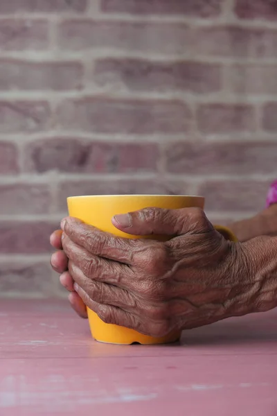 Mulheres seniores mão segurando caneca cor amarela , — Fotografia de Stock