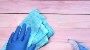 Elinde sprey şişesi tutan mavi lastik eldivenler. 