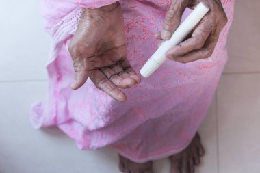 Üst düzey Asyalı kadın evde kan şekerini ölçüyor.