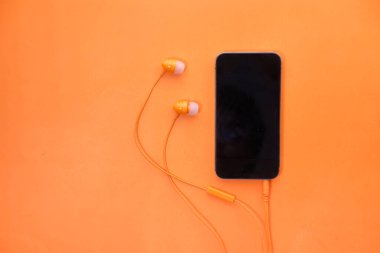akıllı telefon ve kulaklık turuncu arka planda .