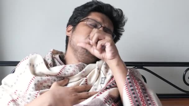Грустный молодой человек с гриппом, завернутый в теплое одеяло — стоковое видео