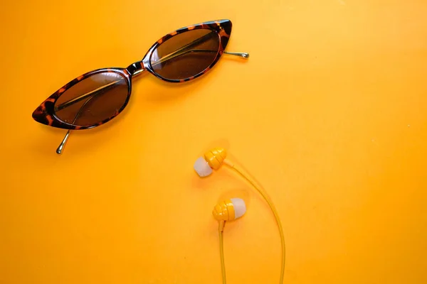 Écouteurs et lunettes de soleil sur fond orange, vue de dessus — Photo