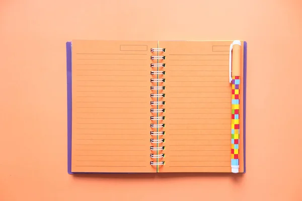 Vista de alto ângulo de notebook com caneta sobre fundo laranja — Fotografia de Stock