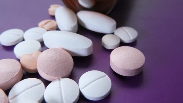 Frasco de pastillas blancas y medicina sobre fondo púrpura — Vídeo de stock