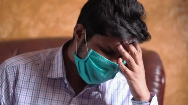 Um homem doente com uma máscara no rosto sofrendo dor de cabeça — Vídeo de Stock
