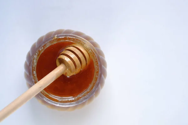 Cucchiaio in un vaso di vetro di miele su sfondo bianco . — Foto Stock