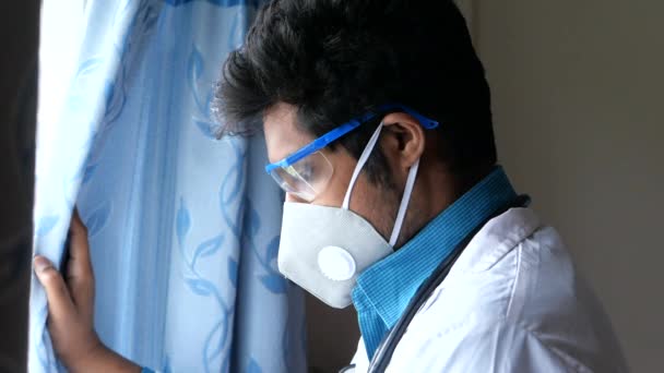 Médecin portant un masque de protection du visage regardant par la fenêtre — Video