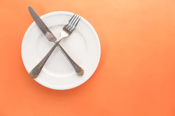 Plato vacío con tenedor y cuchillo en naranja  . — Foto de Stock