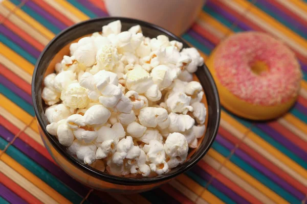 Solony popcorn w misce i pączek na stole — Zdjęcie stockowe