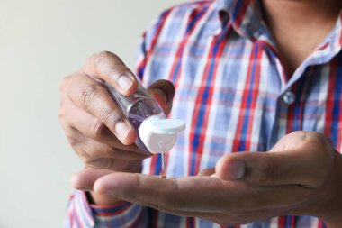 Virüsü önlemek için el dezenfektanı kullanan sıradan giysili genç bir adam. 