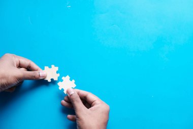 Yapboz parçasını birleştirmeye çalışan iki el