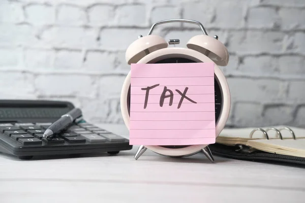 the concept tax payment. the sticky note with tax word on clock