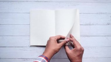 İnsan elinin üst görünümü bir sayfayı çeviriyor.