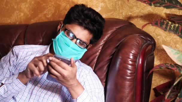 Больной человек в маске на лице использует смартфон дома — стоковое видео