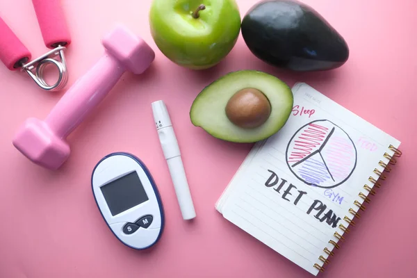 Alat ukur gula darah, dumbbell dan notepad pada pink — Stok Foto