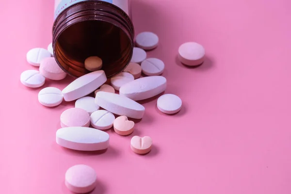 Flaska färgglada piller på rosa bakgrund — Stockfoto