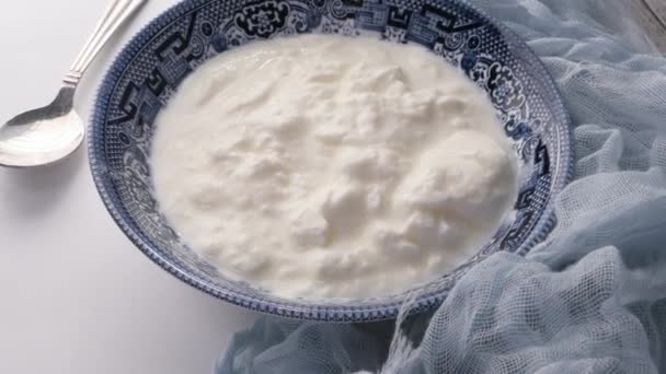 Close up of fresh yogurt in a bowl on color background — Stock Video