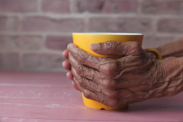 Close up de mulheres idosas mão segurando uma caneca . — Fotografia de Stock