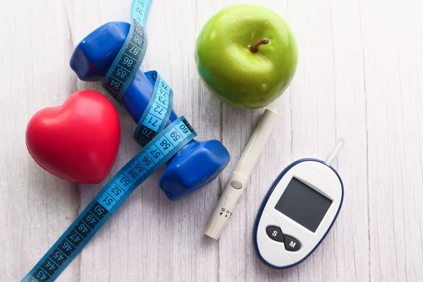  Kan şekeri ölçüm aletleri, dambıl ve elma masada. 