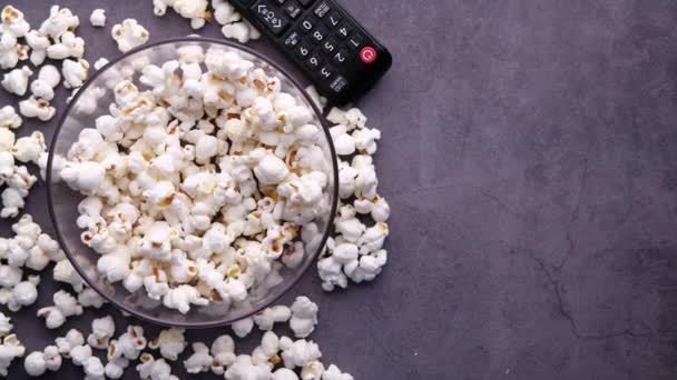 Vedere de sus a popcorn într-un castron și telecomandă TV pe masă — Videoclip de stoc