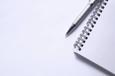Not defterinin üst görünümü ve beyaz üzerine boşluklu bir kalem 