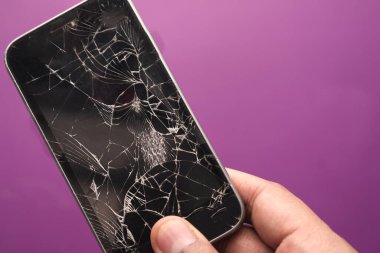 Renkli arkaplanda kırık akıllı telefonu tutan el. 