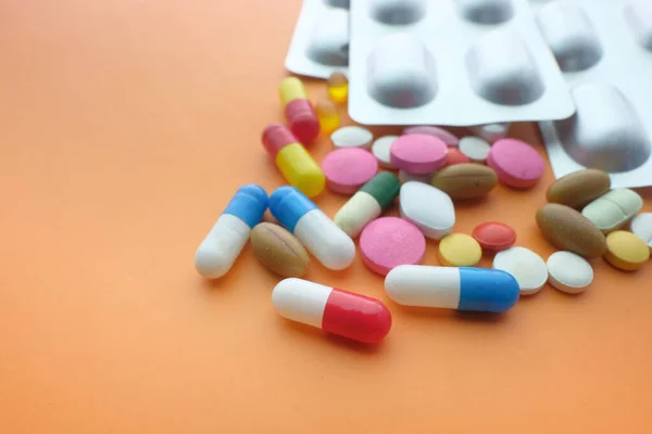 Pillole colorate e blister su sfondo arancione — Foto Stock