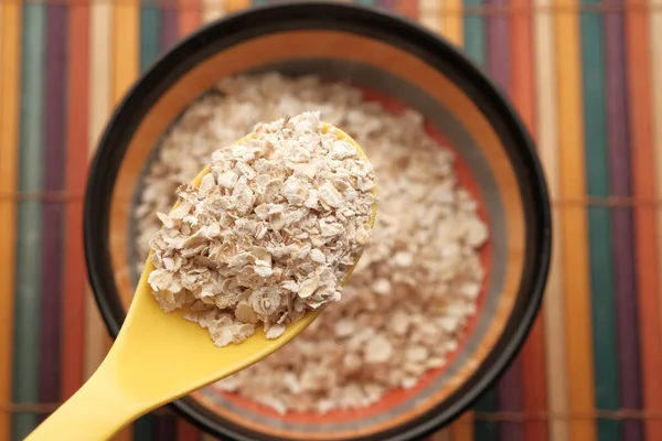 Close up of oats flakes on spoon on table — Stock Photo, Image