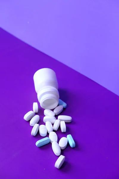 White pills spilling on purple background, Top view — Stock Photo, Image