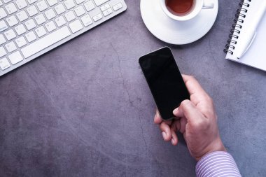 Genç adam elinde boş ekranlı akıllı telefonu tutuyor. 