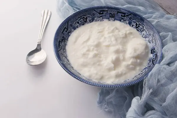 Närbild av färsk yoghurt i en skål på färg bakgrund — Stockfoto