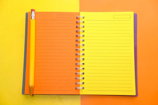 Ανοιχτό πολύχρωμο σημειωματάριο και μολύβια στο φόντο χρώματος — Φωτογραφία Αρχείου
