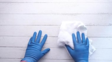 Mavi lastik bir eldiven verin, tahta bir masaya silin.