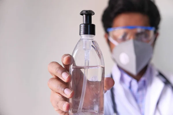 Γιατρός με μάσκα προσώπου που κρατά απολυμαντικό με χώρο αντιγραφής — Φωτογραφία Αρχείου