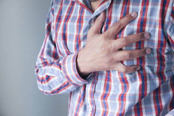 man with chest pain on gray background