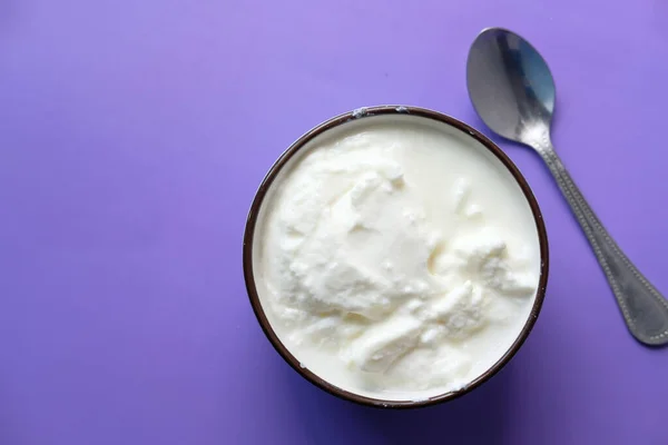 Закрытие свежего йогурта в миске на цветном фоне — стоковое фото