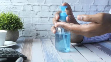 İşadamı ofis odasında el dezenfektanı kullanıyor..