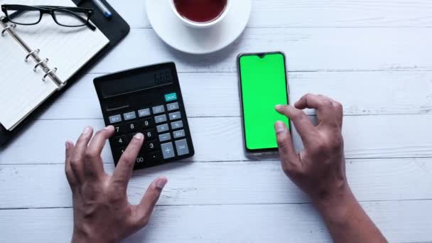 Osoba používající chytrý telefon se zelenou obrazovkou a počítající s kalkulačkou — Stock video