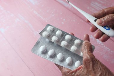 Yaşlı bir kadın elinde su topladı ve termometre tuttu. 