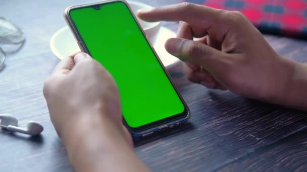 Mano de hombre usando teléfono inteligente con pantalla verde en la mesa — Vídeos de Stock