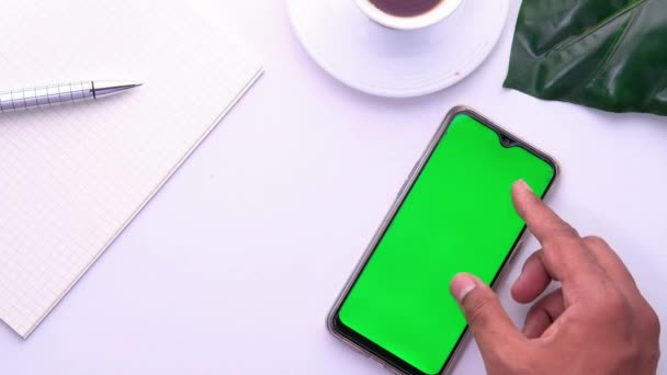 Mano de hombre usando teléfono inteligente con pantalla verde en la mesa — Vídeos de Stock