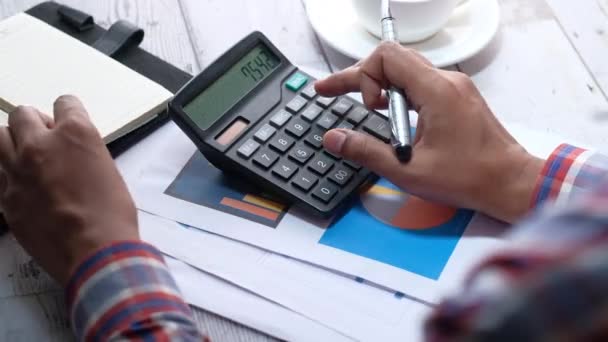 Mano de la persona usando la calculadora y escribiendo en el cuaderno — Vídeo de stock