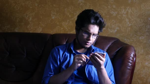 Młody człowiek w sukience casual za pomocą smartfona wewnątrz — Wideo stockowe