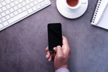 Genç adam elinde boş ekranlı akıllı telefonu tutuyor. 