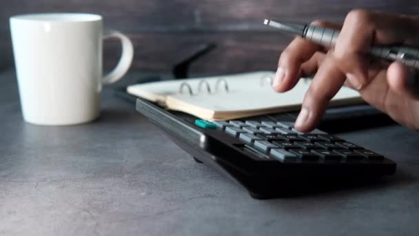 Mano de la persona usando la calculadora y escribiendo en el cuaderno — Vídeos de Stock