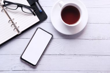  Boş ekranlı akıllı telefon ve tahta arka planda not defteri 