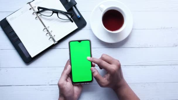 İş adamı eli masada yeşil ekranlı akıllı telefon kullanıyor. — Stok video