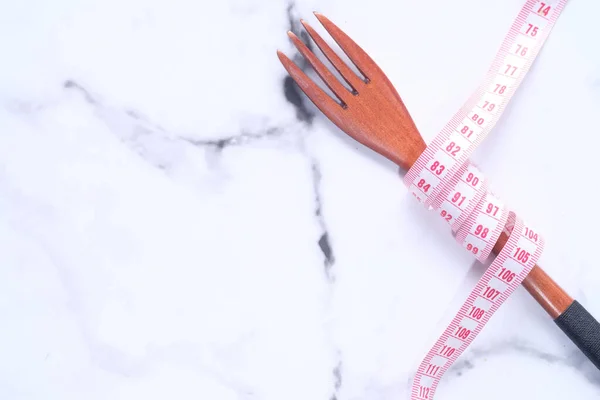 fork with measurement tape on white background